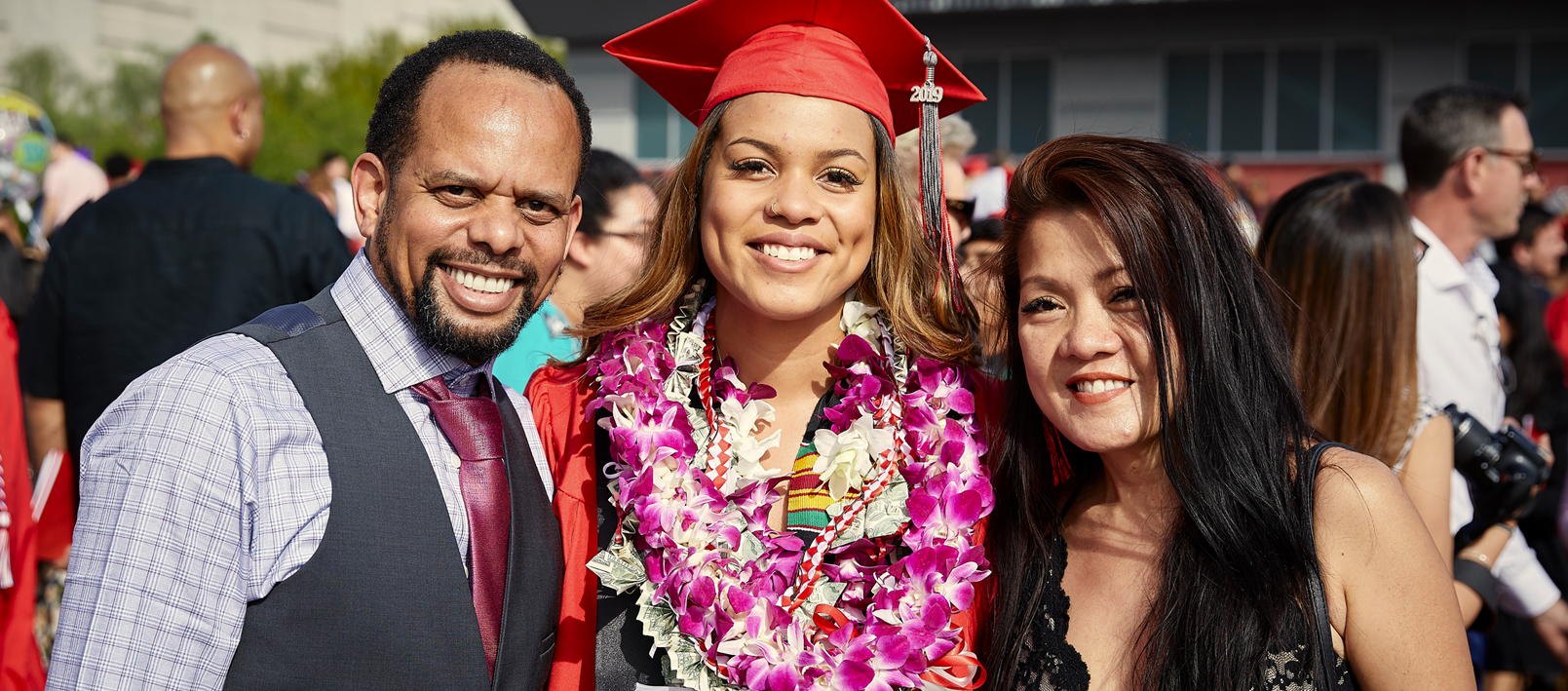 Student smiling with parents at graduation